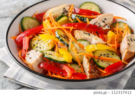 Dietary Chicken salad with fresh vegetables and sesame seeds close-up in a bowl. Horizontal Dietary Chicken salad with fresh vegetables and sesame seeds close-up in a bowl. Horizontal 112337412