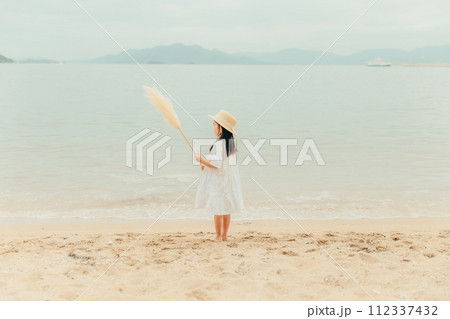 海辺でドライフラワーを持った女の子 112337432