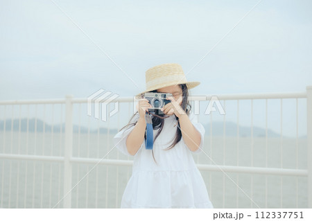 フィルムカメラを持って佇む女の子 112337751