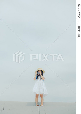 フィルムカメラを持って佇む女の子 112337779