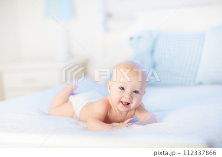 Baby boy on white bed 112337866