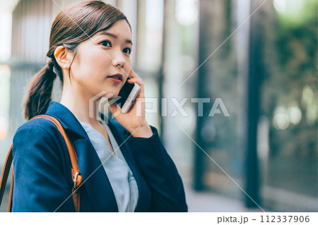 屋外で電話をする若い女性 屋外で電話をする若い女性 112337906