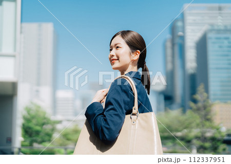 青空とオフィスビルを背景にしたビジネスウーマン 112337951