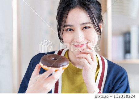 ドーナツを食べる若い女性 112338224