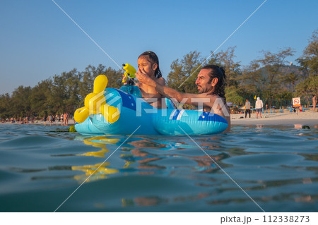 A boy plays with a water gun on a rubber ring. 112338273