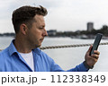 Man holding smartphone in his hand beside the river at port. Nautical and marine concept 112338349