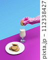 Sanitary pink glove holding a sweet cookie above a glass of milk on a pastel pink and blue background 112338427