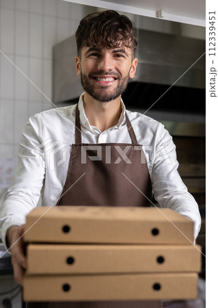 Man holding pizza boxes manages kitchen operations ensuring fast food service 112339451