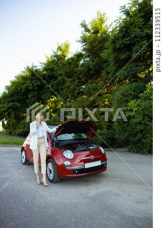 Blonde woman driver using smartphone having problem with her broken car Blonde woman driver using smartphone having problem with her broken car 112339515
