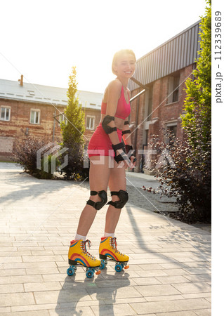 Cute young woman on rollerblades looking enjoyed while skating 112339689