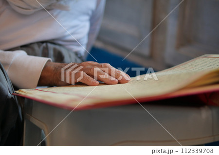 muslim man hand holding Holy book Quran at mosque  112339708