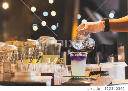 Man making butterfly tea with yuzu juice in a tak away glasses. 112340362