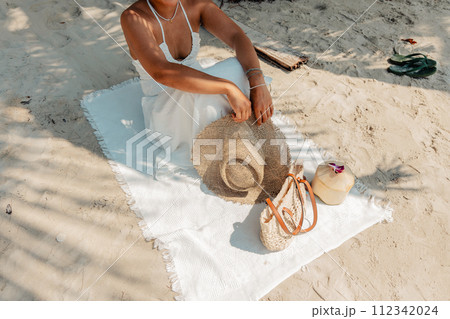 Relaxing at the beach,Woman sitting on beach with hat and bag and coconut 112342024