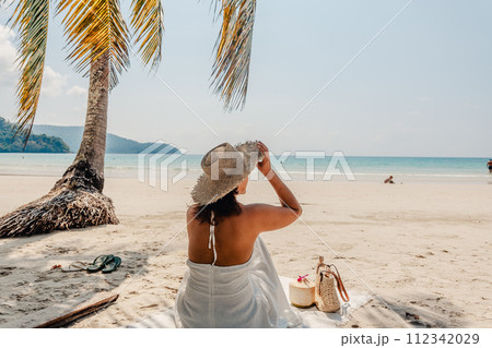 Woman sitting relaxing on the sand at the beach 112342029