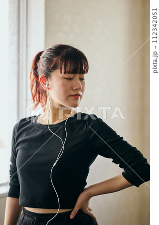 音楽を聴きながらダンスの練習をする若い女性 112342051