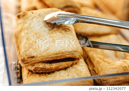 puff pastry in a pastry shop. puff pastry bun. pie with sweet filling. pastry tongs puff pastry in a pastry shop. puff pastry bun. pie with sweet filling. pastry tongs 112342077