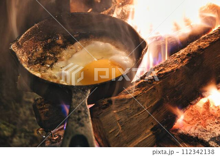 キャンプでの焚き火で目玉焼き キャンプでの焚き火で目玉焼き 112342138