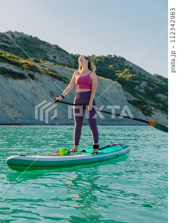 Enjoying woman on stand up paddle board at sea. Woman on SUP board in ocean. Enjoying woman on stand up paddle board at sea. Woman on SUP board in ocean. 112342963