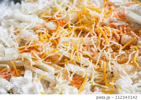 フライパンで焼く大根の千切りにチーズを加える 112343142
