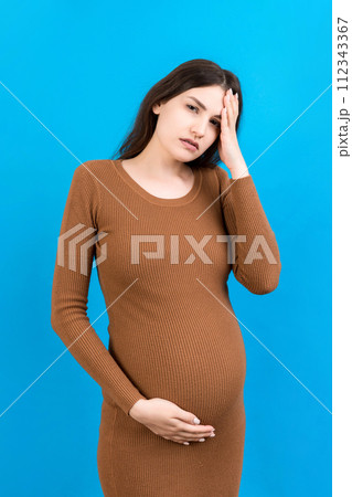 Beautiful young pregnant woman feeling head ache on colored background isolated. Stressed pregnant woman or mother problems Beautiful young pregnant woman feeling head ache on colored background isolated. Stressed pregnant woman or mother problems 112343367