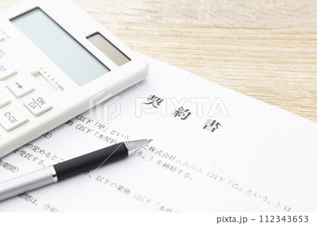 机に置かれた契約書と電卓 112343653