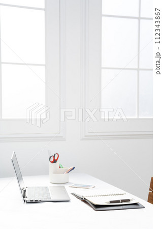 白い窓際にノートパソコンとステーショナリーのあるイメージ 白い窓際にノートパソコンとステーショナリーのあるイメージ 112343867