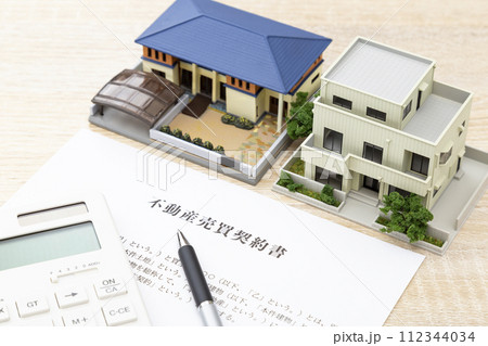 机に住宅模型と契約書 112344034