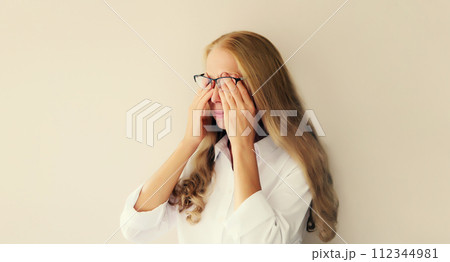 Tired overworked woman employee rubbing her eyes suffering from eye strain, dry eye syndrome Tired overworked woman employee rubbing her eyes suffering from eye strain, dry eye syndrome 112344981