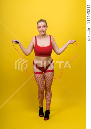 Beautiful fitness female posing on studio background with jumping rope Beautiful fitness female posing on studio background with jumping rope 112345215
