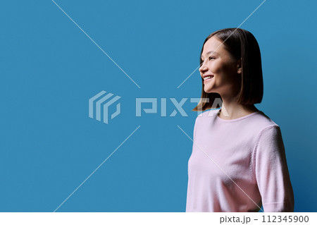 Profile portrait of young smiling woman on blue background 112345900
