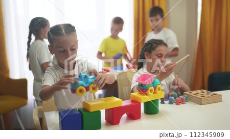 child group playing fishing. children in kindergarten play with toys. happy family kid lifestyle dream concept. a group of children collect building blocks in a kindergarten indoors 112345909