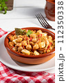 Homemade Ropa vieja, typical Canarian dish of chickpeas stew in earthenware casserole on white table. Vertical format. 112350338