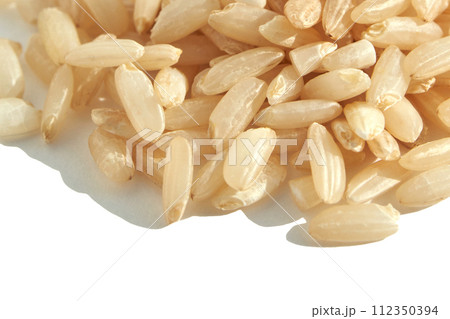 A background of dry brown rice grains showcases the integral, uncooked texture 112350394