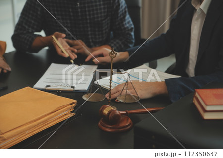 Justice and Law concept. Legal counsel presents to the client a signed contract with gavel and legal law or legal having team meeting at law firm in background 112350637
