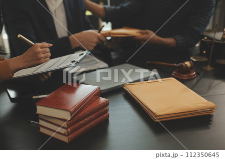 Justice and Law concept. Legal counsel presents to the client a signed contract with gavel and legal law or legal having team meeting at law firm in background 112350645