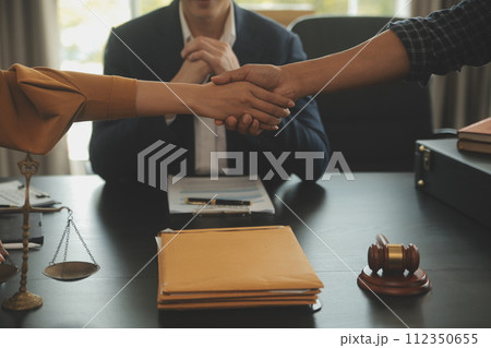 Justice and Law concept. Legal counsel presents to the client a signed contract with gavel and legal law or legal having team meeting at law firm in background Justice and Law concept. Legal counsel presents to the client a signed contract with gavel and legal law or legal having team meeting at law firm in background 112350655