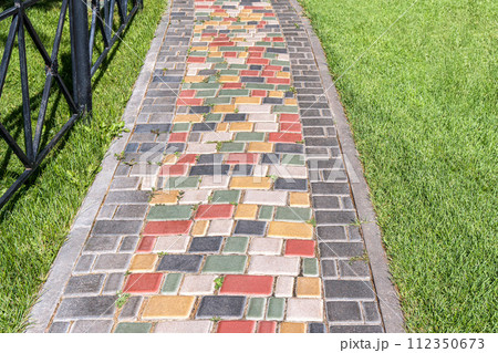 Colorful paved road across lush lawn in summer park. Creative design element of landscaping 112350673
