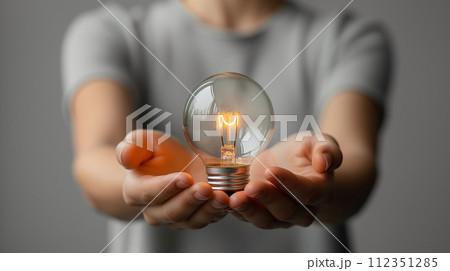 A hand grasps a lightbulb, symbolizing a spark of creativity 112351285