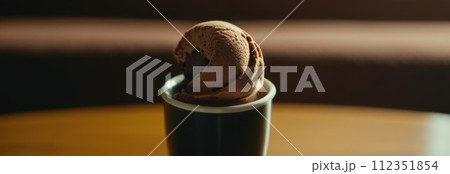 Delicious cup of ice cream sits on table in front of window, basking in natural light. For advertising, banner, relaxation, lifestyle, menu, food, dessert, culinary or cafe themed content. Copy space. 112351854