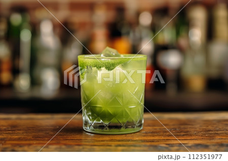 Matcha margarita with ice and rimmed with matcha powder on a bar counter 112351977