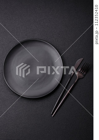 Cutlery fork, knife and spoon on a dark textured concrete background Cutlery fork, knife and spoon on a dark textured concrete background 112352410