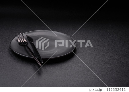 Cutlery fork, knife and spoon on a dark textured concrete background 112352411