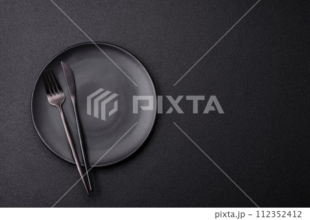 Cutlery fork, knife and spoon on a dark textured concrete background 112352412