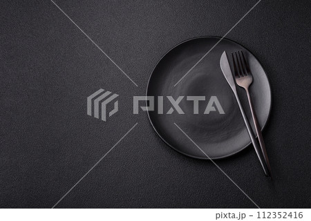 Cutlery fork, knife and spoon on a dark textured concrete background Cutlery fork, knife and spoon on a dark textured concrete background 112352416