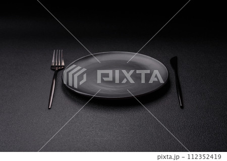 Cutlery fork, knife and spoon on a dark textured concrete background Cutlery fork, knife and spoon on a dark textured concrete background 112352419