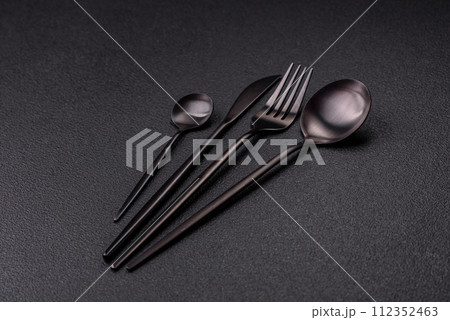 Cutlery fork, knife and spoon on a dark textured concrete background Cutlery fork, knife and spoon on a dark textured concrete background 112352463