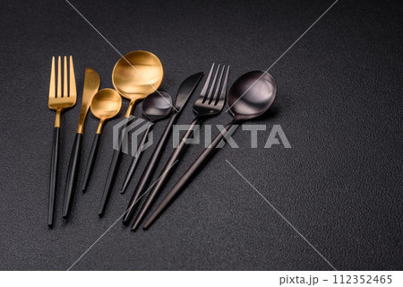 Cutlery fork, knife and spoon on a dark textured concrete background Cutlery fork, knife and spoon on a dark textured concrete background 112352465