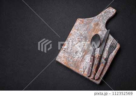 Cutlery fork, knife and spoon on a dark textured concrete background 112352569