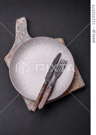 Cutlery fork, knife and spoon on a dark textured concrete background 112352573