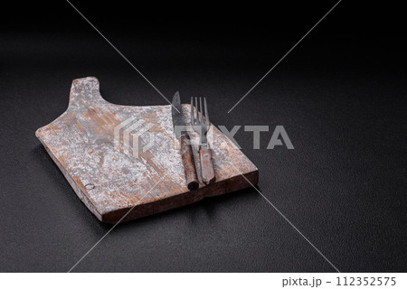 Cutlery fork, knife and spoon on a dark textured concrete background Cutlery fork, knife and spoon on a dark textured concrete background 112352575